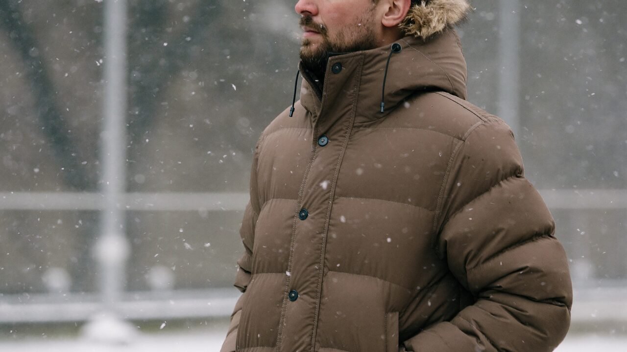 Homme en manteau d'hiver chaud dans une rue enneigée